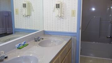 A bathroom with two sinks, a mirror, and a shower.