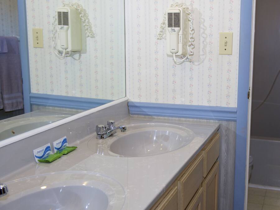 A bathroom with two sinks, a mirror, and a shower.