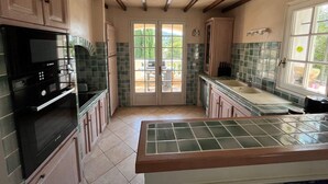 A kitchen with a built-in Bosch microwave, green-tiled backsplash, wooden cabinets, and a large window. - Villa Standing 160m2 piscine, Mer proche Bandol Sanary Le Castelet St-Cyr/mer  (La Cadière-D'azur)