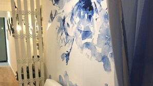 En moderne stue med en hvid sofa, blå puder og et stort, abstrakt maleri i blå og hvide farver på væggen.