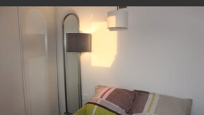 A bedroom with a bed, pillows, a bedside lamp, and a mirror. - T2 apartment near beach, swimming pool, tennis (Bidart)