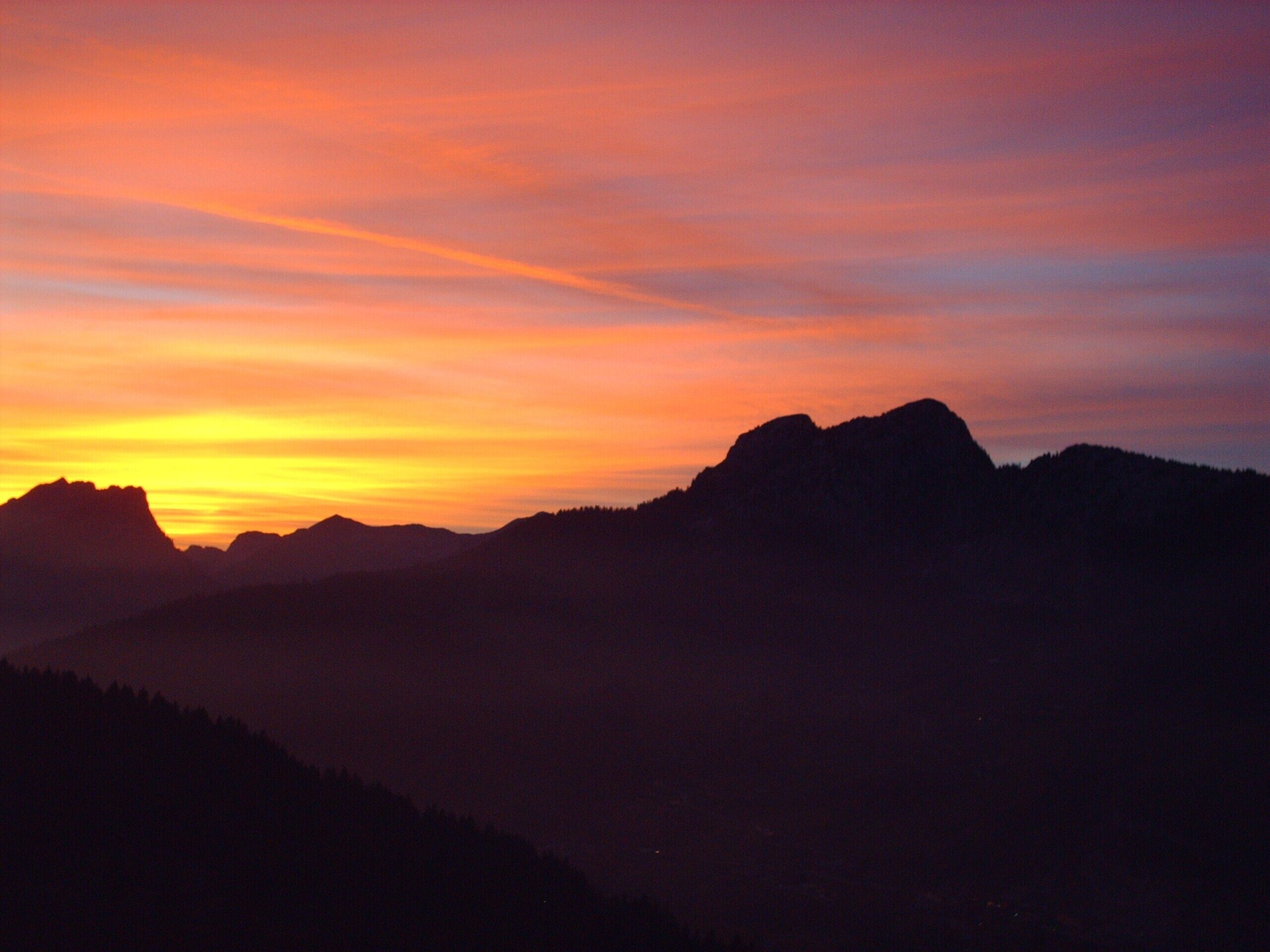 La silhouette d’une chaîne de montagnes se détachant sur le ciel au coucher du soleil.