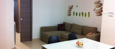 A compact living space with a sofa, a dining table, and a small kitchen area.