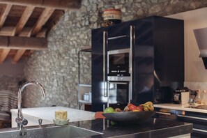 A kitchen with a stone wall, a modern sink, and a bowl of fruit on the counter. - Chalet - Saint André (Saint-André)