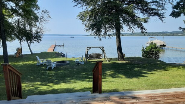 Una terrazza con vista su un lago, arredi da esterno e un’altalena.