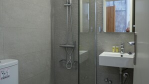 Une salle de bain moderne avec une douche à parois de verre, un lavabo blanc et des toilettes.