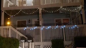 Um edifício com vários andares, varandas, luzes de corda e portão.