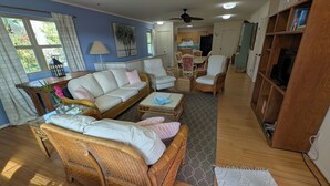 Una sala de estar con sofá, sillones, una mesa de centro y una estantería.