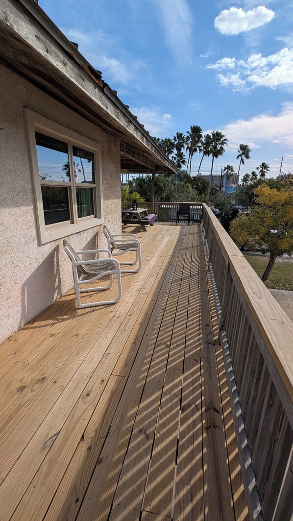 Una terraza de madera con barandilla, una mesa y sillas.