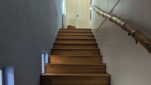 Una escalera de madera con barandilla, que lleva a una puerta blanca en la parte superior.