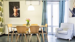 A dining area with a table, chairs, a vase with flowers, and a striped armchair.