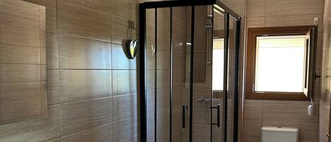 A bathroom with a shower enclosure, a toilet, and a bidet.