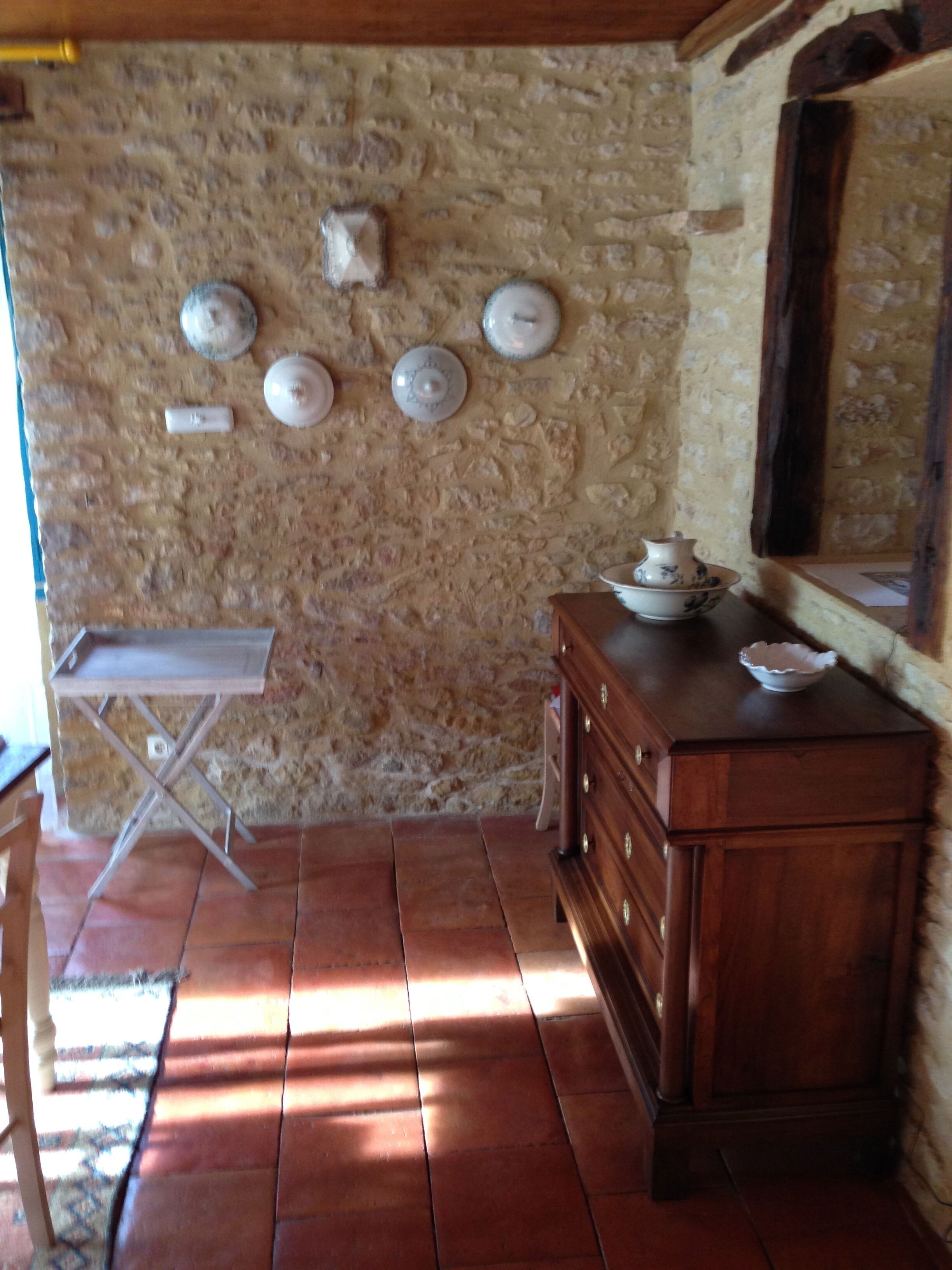 A rustic kitchen with a stone wall, a wooden cabinet, and a small table.
