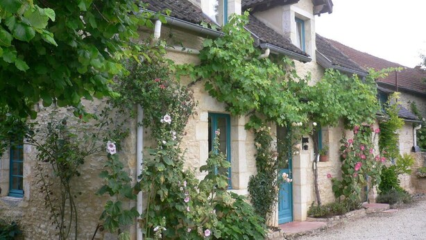 A stone building with a traditional architectural style, featuring a pitched roof and multiple windows with blue shutters.