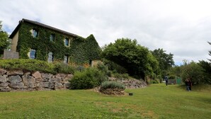 A stone wall, a grassy area, and a building with ivy-covered walls.