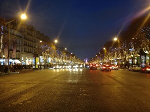 Una escena nocturna en la calle con adoquines y farolas iluminadas.