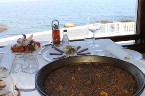 Une table à manger avec un grand plat de ragoût, une bouteille d’eau et un verre de vin.