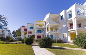 Un hôtel à plusieurs étages, doté de balcons, d’une cour intérieure et surplombant un ciel d’un bleu éclatant.