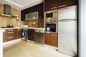 Une cuisine moderne dotée d’appareils électroménagers en acier inoxydable, de meubles en bois et d’un four encastré.