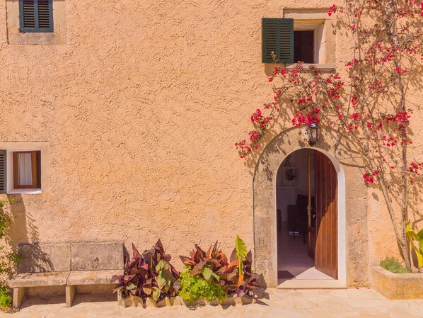 Um edifício com fachada texturizada, porta de madeira e janela com persianas.