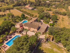 Vue aérienne d’un vaste domaine comprenant une piscine, plusieurs bâtiments et une végétation luxuriante.