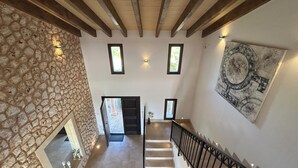 A multi-level interior with stone walls, wooden beams, and a staircase. - Luxury villa with panoramic sea views for 12 people, large pool, BBQ house  (Cala Murada)