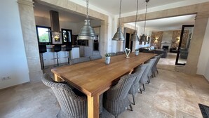 A spacious dining area with a long wooden table, wicker chairs, and pendant lighting. - Luxury villa with panoramic sea views for 12 people, large pool, BBQ house  (Cala Murada)
