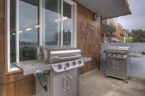 Outdoor cooking area with two grills, a flat top and a round top, both with multiple burners and controls.