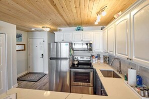 Compact kitchen with modern appliances, including a refrigerator, oven, and microwave, and ample cabinetry.