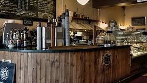 A counter with a wooden finish, a menu board above it, and a coffee machine to the left. - Spacious Family-Friendly Home Near UBC—Hot Tub, Sauna & A/C (Vancouver)