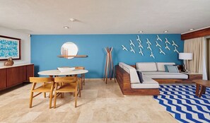 Un soggiorno moderno con una parete azzurra, uno specchio rotondo, un tavolo da pranzo in legno con sedie, un divano con cuscini e un tappeto decorato.
