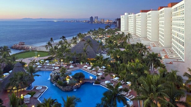 Ein Resort mit Pool, Palmen und Blick auf den Ozean.