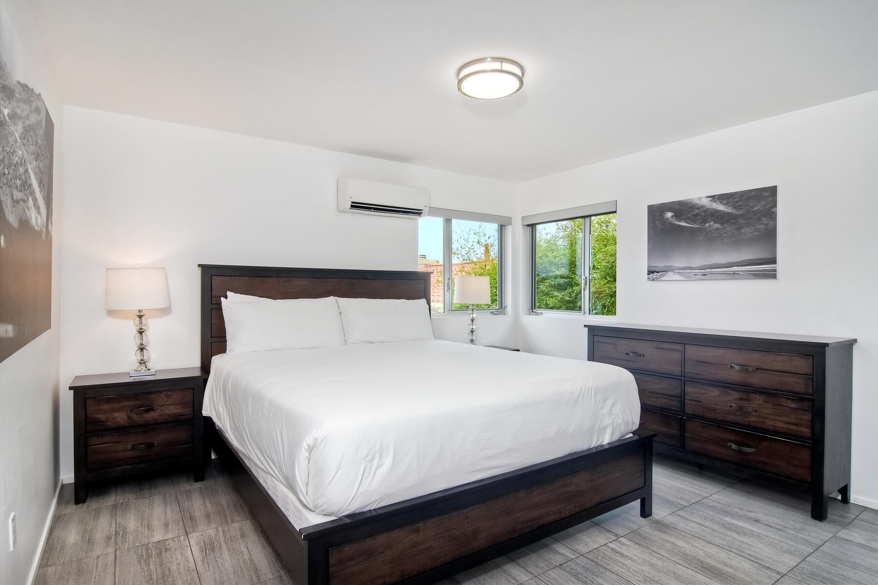 A modern bedroom with a large bed, a dresser, and a ceiling light.