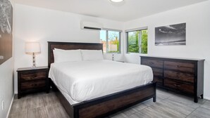 A modern bedroom with a large bed, a dresser, and a ceiling light. - Sand (1 bedroom / 1 bath) (Carlsbad)
