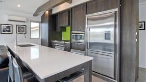 A modern kitchen with a large island, stainless steel appliances, and dark wood cabinetry. - Sand (1 bedroom / 1 bath) (Carlsbad)
