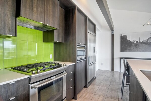 A modern kitchen with a gas stove, oven, built-in microwave, and a stainless steel refrigerator. - Sand (1 bedroom / 1 bath) (Carlsbad)