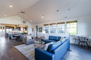 A spacious living area with a blue sofa, a glass coffee table, and a dining table with chairs.