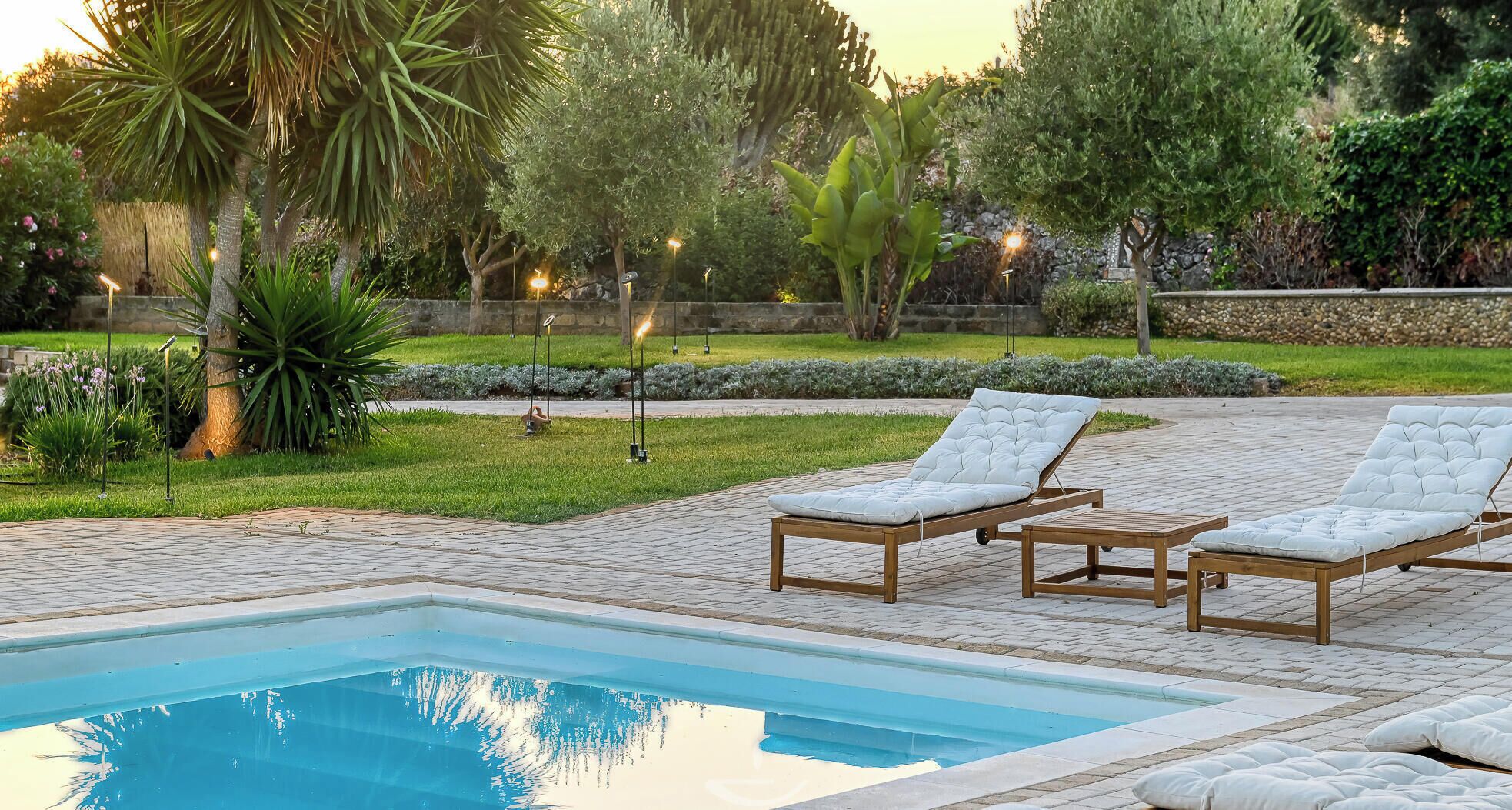 A swimming pool with lounge chairs and a well-maintained garden.