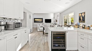 Eine moderne Küche mit weißen Schränken, Edelstahlgeräten und einem Weinkühlschrank.
