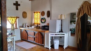 Une cuisine rustique avec des meubles en bois, un évier, un réfrigérateur et un coin repas comprenant une chaise et une table.