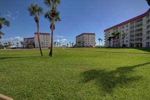 Un hotel de varios pisos, techo plano y césped bien cuidado con palmeras.