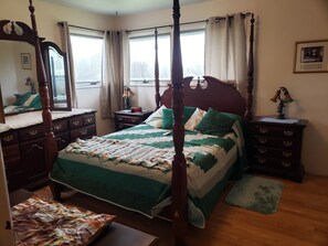 A four-poster bed with a green and white quilt, wooden nightstands, a dresser, and a window with curtains. - Private 20 Acres with Wisconsin Creek flowing through the front yard. (Twin Bridges)