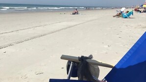 Uma praia com uma espreguiçadeira azul e uma toalha colorida.