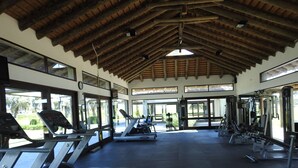 Ein Fitnessstudio mit Laufbändern, Kraftgeräten und einem großen Fensterfront.