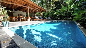 Een buitenzwembad, ligstoelen bij het zwembad