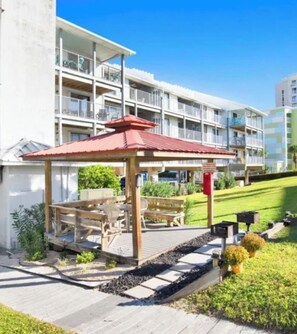 A multi-story hotel with balconies, a covered outdoor seating area, and a well-maintained lawn.