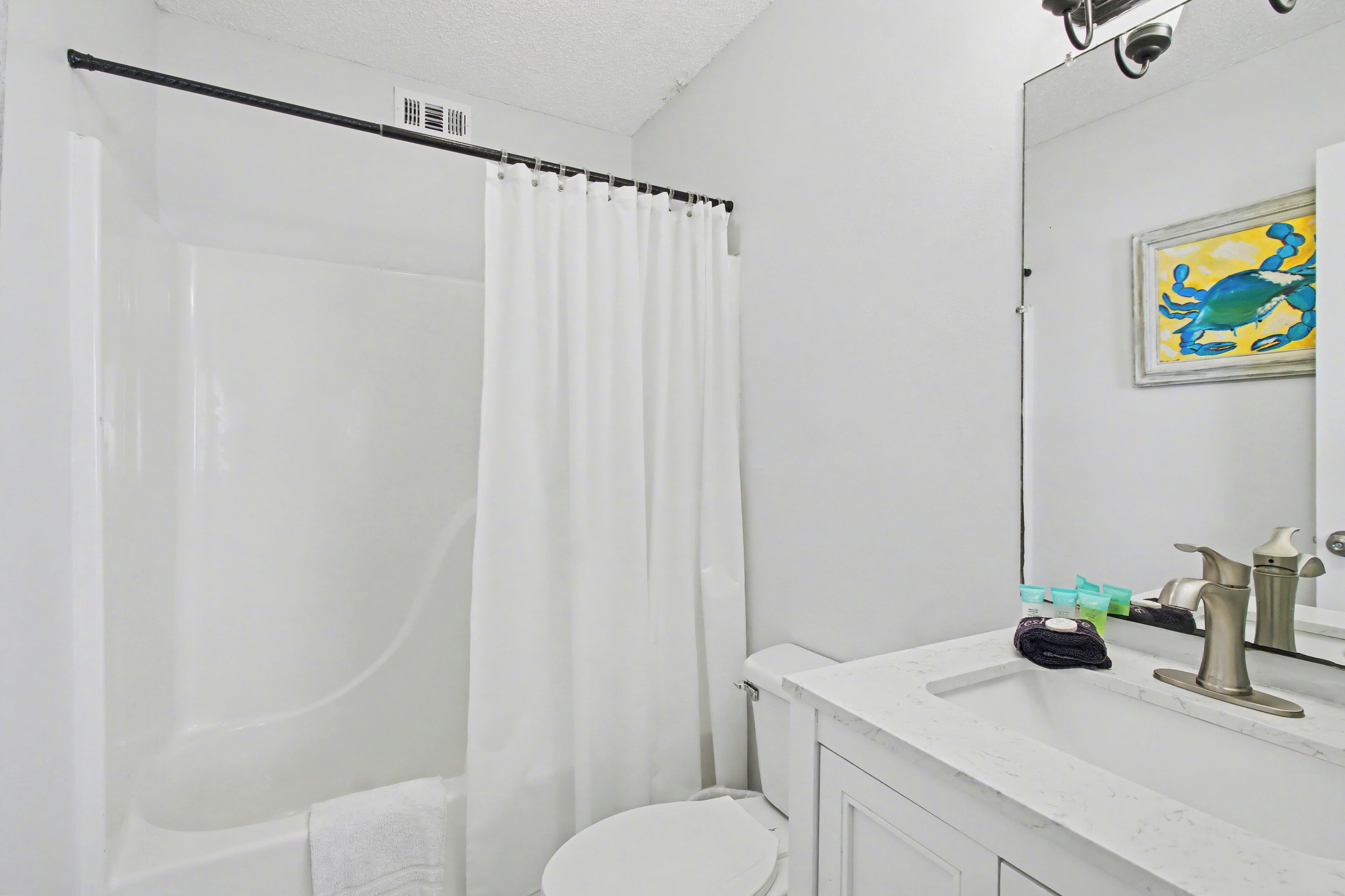 A bathroom with a bathtub, toilet, and a sink with toiletries.