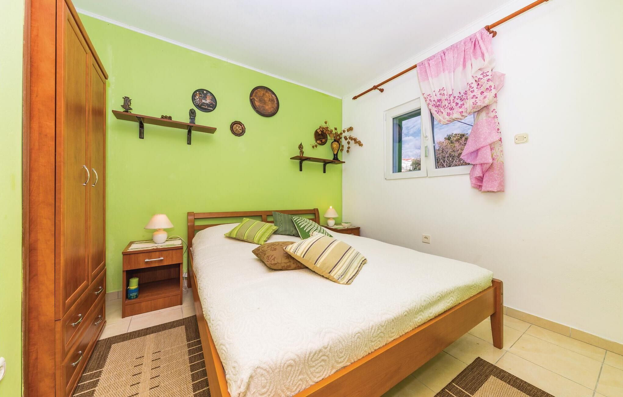 Une chambre à coucher comprenant un lit, des tables de chevet, une armoire, une fenêtre avec un rideau et des éléments de décoration murale.