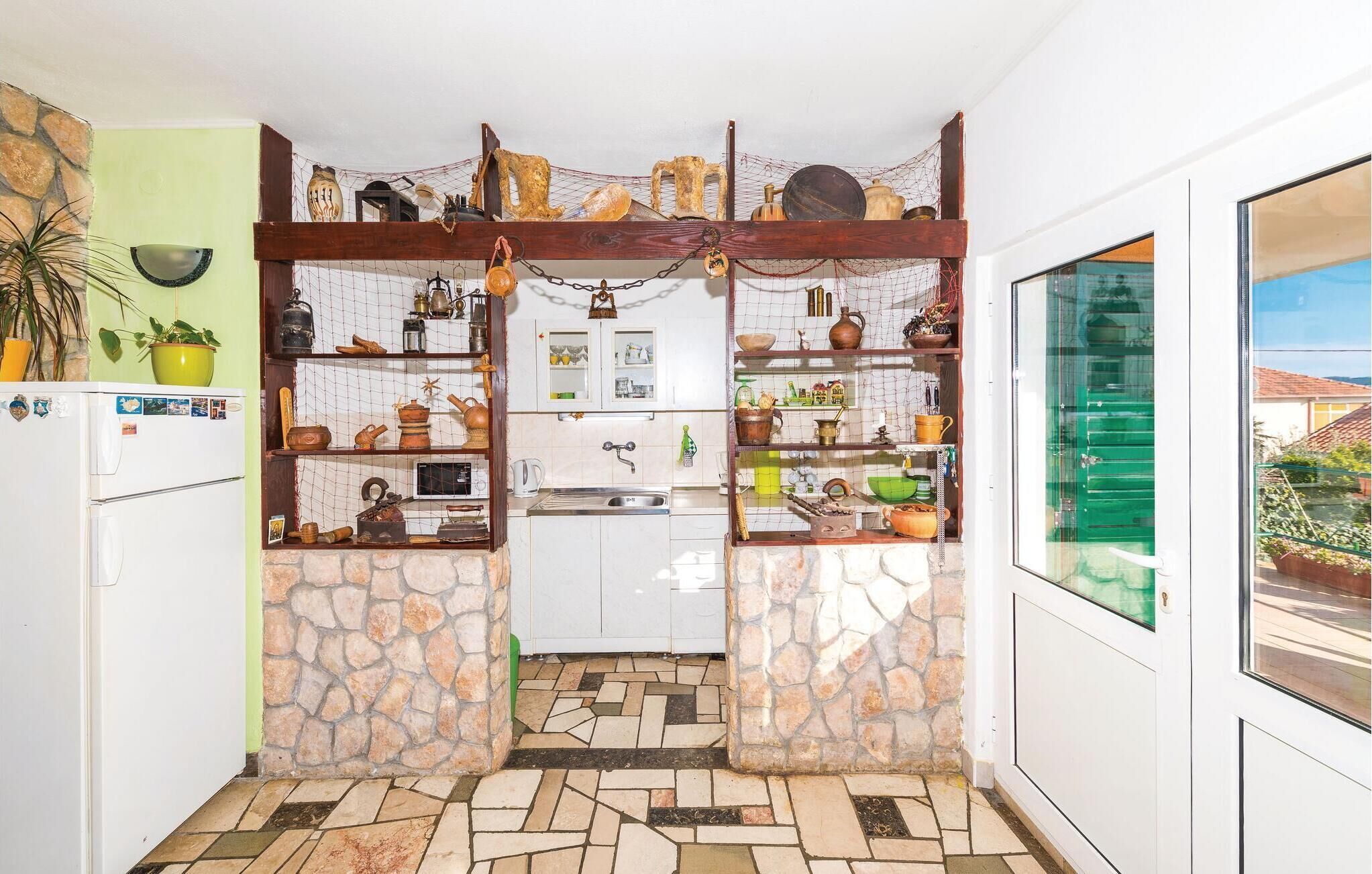 Een compacte keuken met stenen muren, een houten spouwmuur en diverse keukengerei en decoraties.