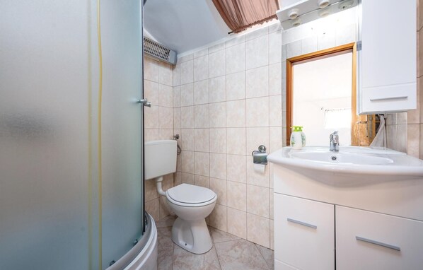A bathroom with a toilet, sink, and shower.